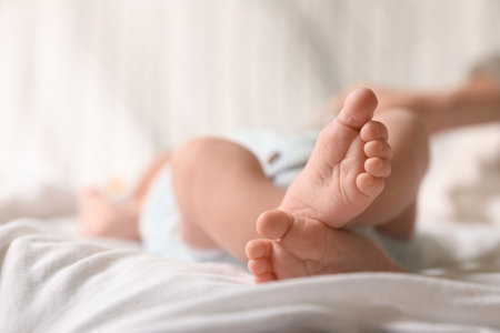Cute newborn baby lying on bed, closeup of legs. Space for textの写真素材