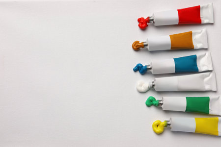 Tubes with oil paints on white canvas, flat lay. Space for textの写真素材