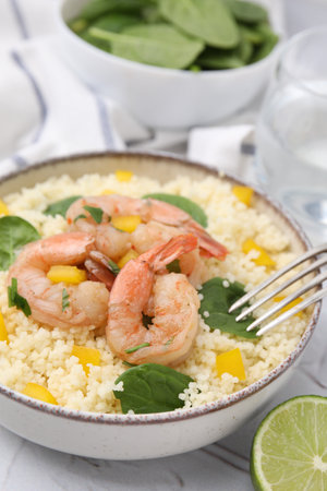 Tasty couscous with shrimps, bell pepper and basil on white textured table, closeupの写真素材