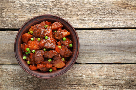 Delicious beef stew with carrots, peas and potatoes on wooden table, top view. Space for textの写真素材