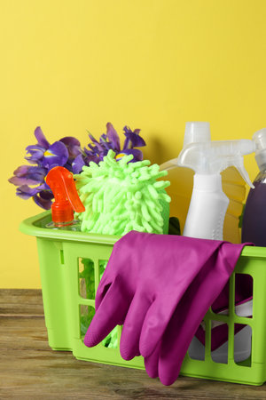 spring cleaning. Basket with detergents, flowers and tools on wooden tableの写真素材