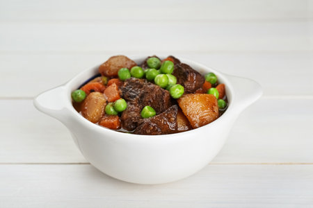 Delicious beef stew with carrots, peas and potatoes on white wooden table, closeupの写真素材