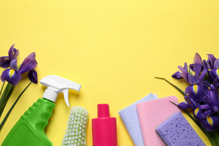 spring cleaning. Detergents, flowers, sponge, brush and rags on yellow background, flat lay. Space for textの写真素材