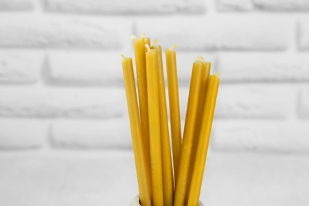 Church candles near white brick wall, closeupの写真素材