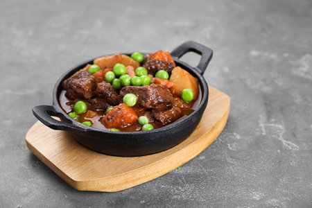 Delicious beef stew with carrots, peas and potatoes on gray table, closeup. Space for textの写真素材