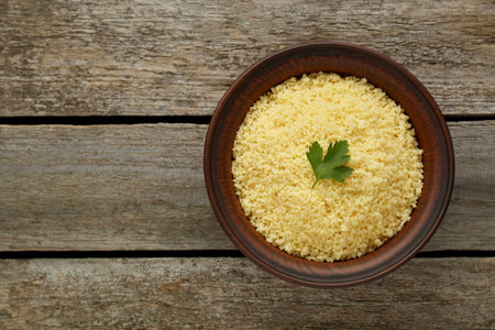Tasty couscous with parsley on wooden table, top view. Space for textの写真素材