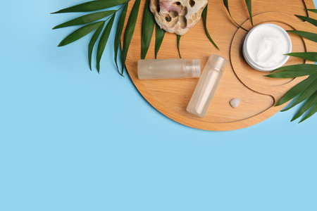 Different cosmetic products, palm leaves and stones on light blue background, flat lay. Space for textの写真素材