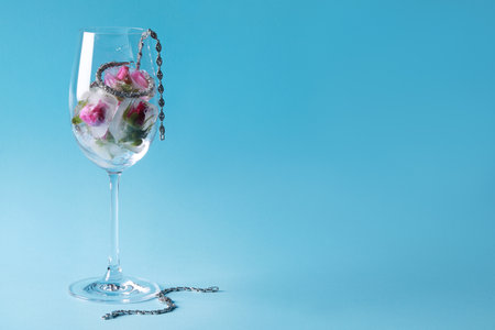 elegant jewelry. Stylish presentation with luxury earrings, bracelets and frozen roses in glass on light blue background. Space for textの写真素材