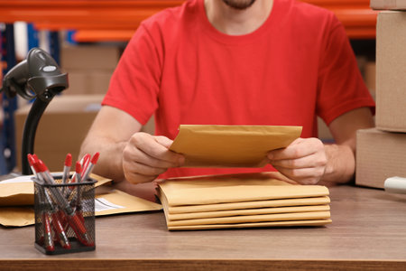 Post office worker with adhesive paper bags at counter indoors, closeupの写真素材