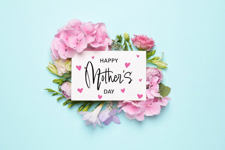 Happy Mother's Day greeting card and beautiful flowers on pale light blue background, flat layの写真素材