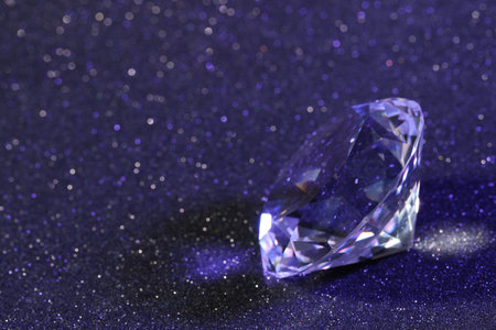 Beautiful dazzling diamond on violet glitter background, closeup. Space for textの写真素材