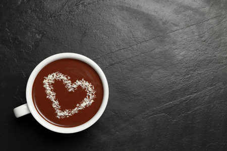 Cup of hot chocolate with heart shaped decoration on black table, top view. Space for textの写真素材