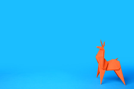 origami art. Handmade orange paper deer on light blue background, space for textの写真素材