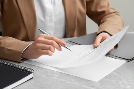 Woman signing document at light gray marble table, closeupの写真素材