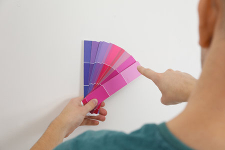 Man with palette choosing color for painting wall indoors, closeup. interior designの写真素材