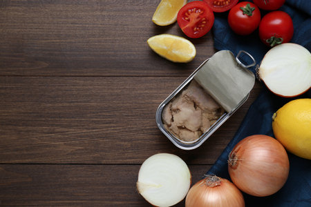 Flat lay composition with tin can of tasty cod liver and different products on wooden table. Space...