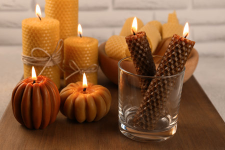 Beautiful burning beeswax candles on wooden tableの写真素材