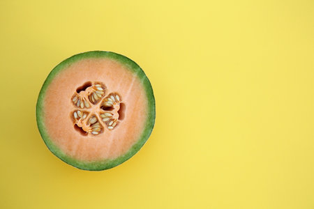Half of fresh ripe cantaloupe melon on yellow background, top view. Space for textの写真素材