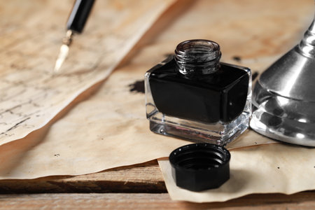 Open inkwell and vintage parchment on wooden table, closeupの写真素材