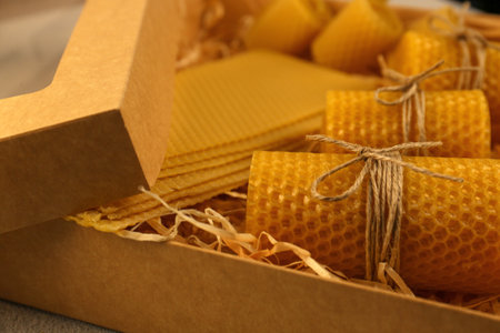 Beautiful yellow beeswax candles and sheets in box, closeupの写真素材