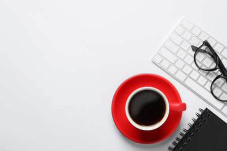 Cup with aromatic coffee, notepad, keyboard and glasses on white background, flat lay. Space for textの写真素材