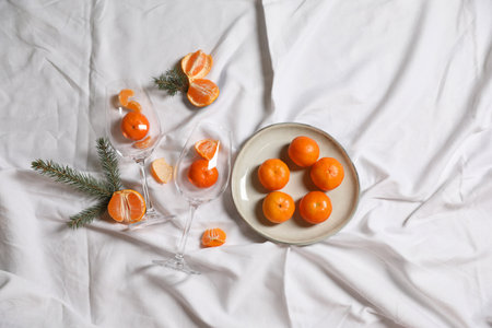 Delicious fresh ripe tangerines and glasses on white bedsheet, flat layの写真素材