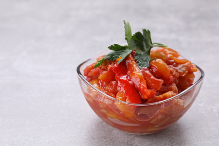 Delicious lecho with parsley in glass bowl on light gray tableの写真素材