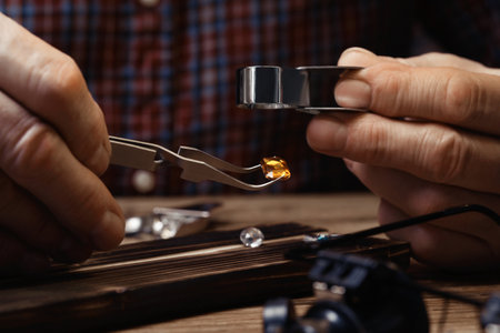 Professional jeweler working with gemstone at wooden table, closeup