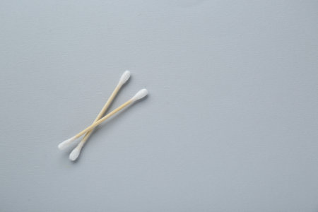 Two wooden cotton buds on light gray background, flat lay. Space for textの写真素材