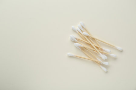 Heap of wooden cotton buds on beige background, flat lay. Space for textの写真素材