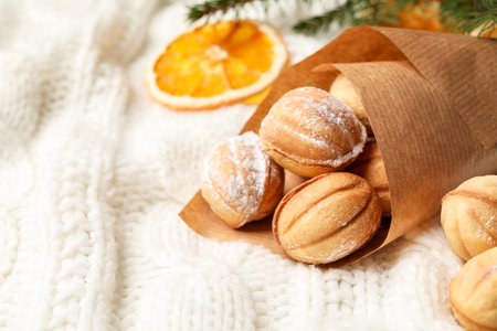 Delicious nut shaped cookies and dried orange slice on white knitted fabric, closeup. Space for textの写真素材