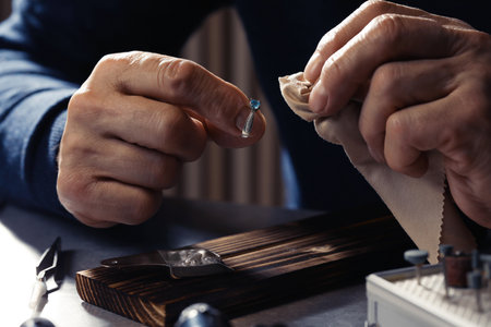 Professional jeweler working with ring at table, closeup