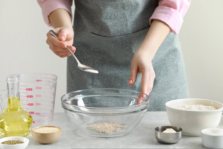 Woman making dough for traditional grissini at light gray marble table indoors, closeup
