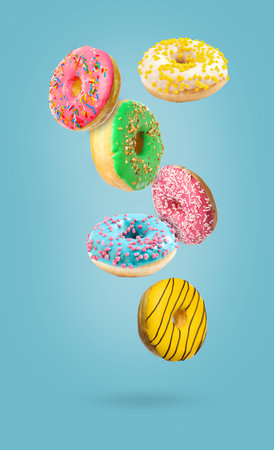 Sweet tasty donuts falling on light blue backgroundの写真素材