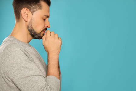 Man with clasped hands praying on turquoise background. Space for textの写真素材