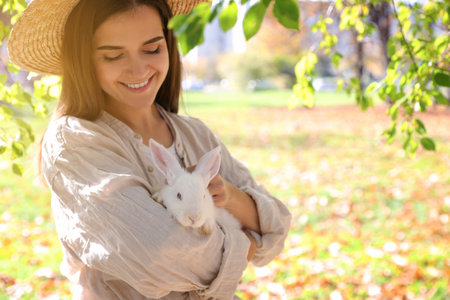 Woman holding cute white rabbit in park, space for textの写真素材