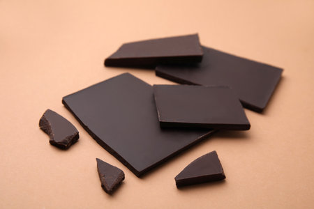 Broken tasty chocolate bar on brown background