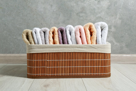 Laundry basket with clean terry towels on floor near gray wallの写真素材