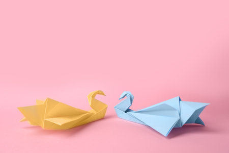 origami art. Beautiful paper swans on pink backgroundの写真素材