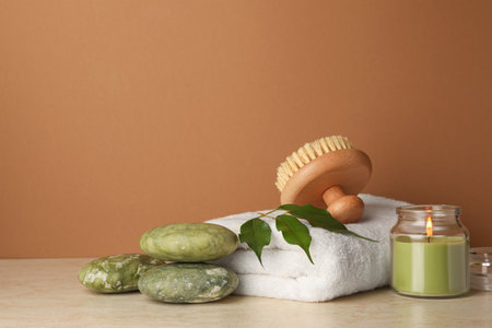Composition with different spa products and burning candle on beige table against brown background. Space for textの写真素材