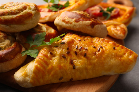 Different delicious puff pastry with tasty filling on wooden board, closeupの写真素材