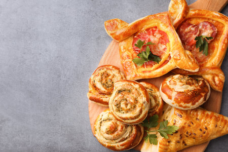 Various delicious puff pastry with tasty filling on gray table, top view. Space for textの写真素材