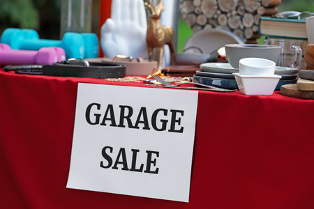 Paper with sign Garage sale and many different items on red tableclothの写真素材