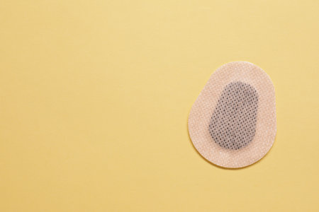 Contraceptive patch on yellow background, top view. Space for text