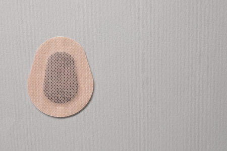Contraceptive patch on light gray background, top view. Space for text