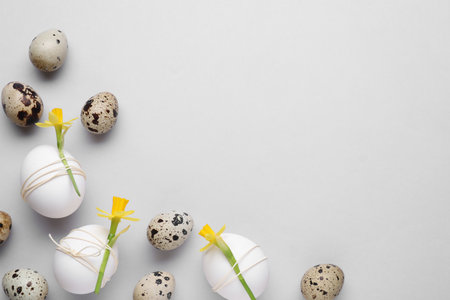 Easter eggs decorated with flowers on light gray background, flat lay. Space for text