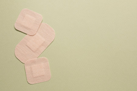 Different contraceptive patches on green background, flat lay. Space for text