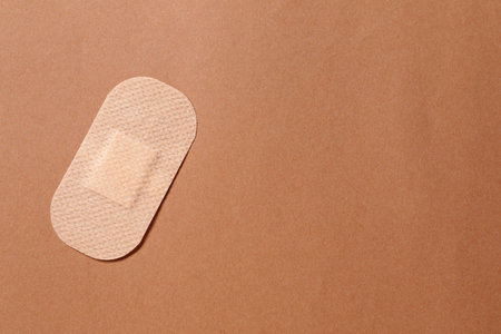 Contraceptive patch on light brown background, top view. Space for text