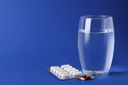 Different antidepressants and glass of water on blue background, space for textの写真素材