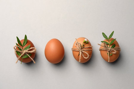 Chicken eggs and natural decor on light gray background, flat lay. happy easter